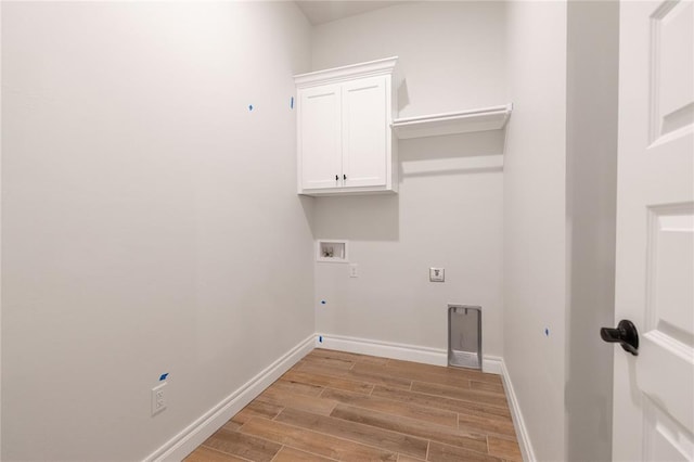 clothes washing area featuring hookup for a washing machine, cabinet space, gas dryer hookup, light wood-type flooring, and baseboards