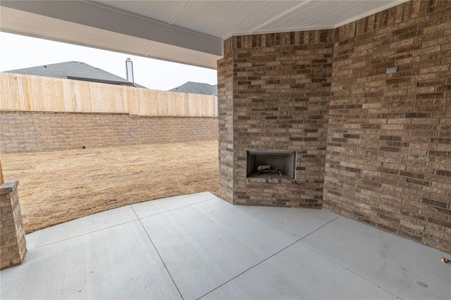 view of patio / terrace with an outdoor brick fireplace and fence