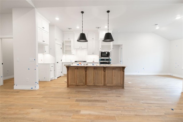 kitchen featuring white cabinets, open floor plan, oven, built in microwave, and light wood-type flooring