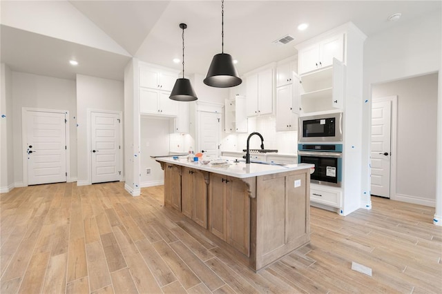 kitchen with light wood finished floors, visible vents, stainless steel oven, a sink, and built in microwave