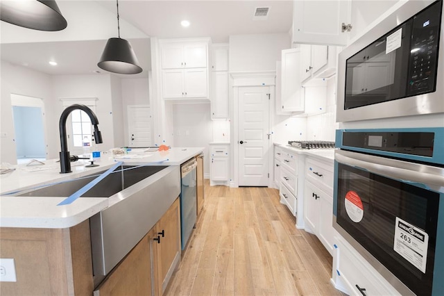 kitchen featuring visible vents, white cabinetry, appliances with stainless steel finishes, light wood-type flooring, and decorative light fixtures