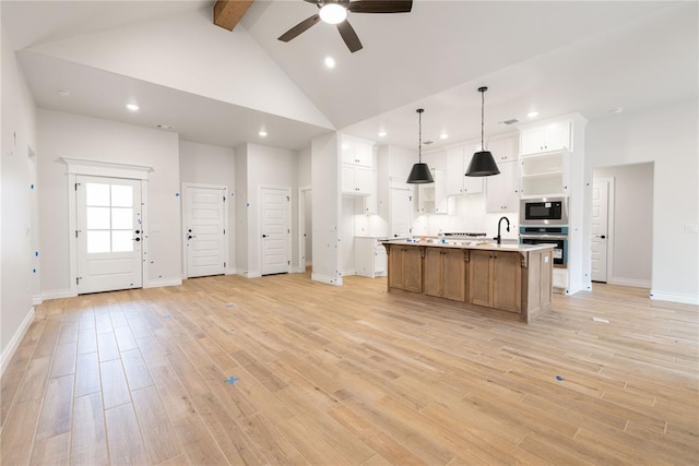 kitchen featuring appliances with stainless steel finishes, open floor plan, high vaulted ceiling, and light wood-style flooring