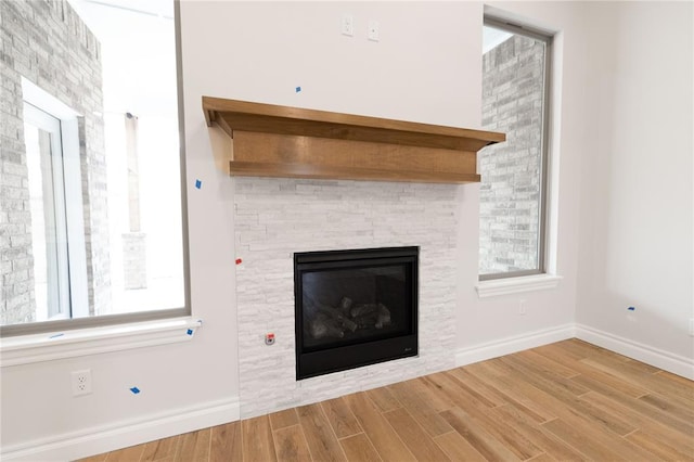 interior space featuring a stone fireplace, baseboards, and wood finished floors