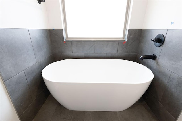 full bath with a freestanding tub, tile walls, and tile patterned floors