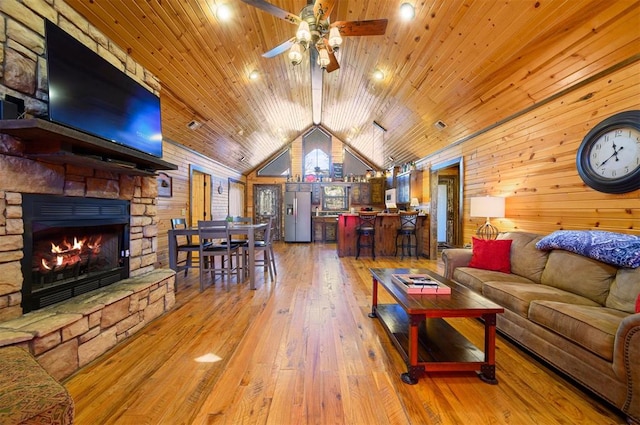 living room with vaulted ceiling, ceiling fan, wood-type flooring, wooden ceiling, and wood walls