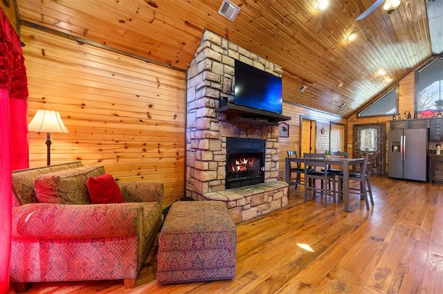 living room with wood walls, vaulted ceiling, a fireplace, wood ceiling, and hardwood / wood-style flooring