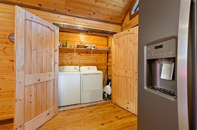 clothes washing area with wood ceiling, washer and dryer, light hardwood / wood-style floors, and wood walls