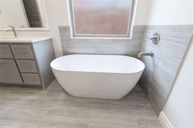 bathroom featuring vanity, a washtub, and tile walls