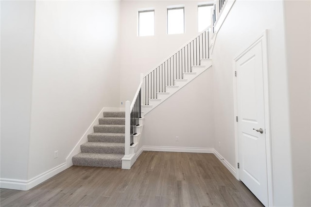 stairs featuring a high ceiling and wood-type flooring