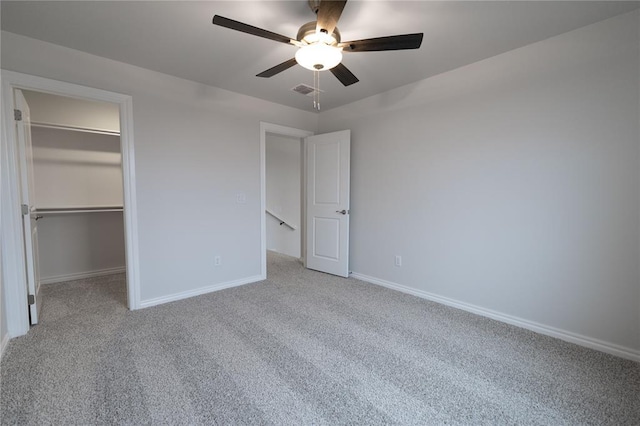 unfurnished bedroom featuring a spacious closet, light carpet, ceiling fan, and a closet