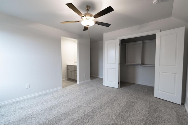 unfurnished bedroom with ceiling fan, a closet, ensuite bath, and light carpet