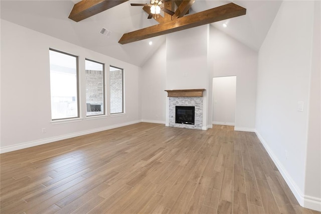 unfurnished living room with a stone fireplace, high vaulted ceiling, beamed ceiling, ceiling fan, and light hardwood / wood-style flooring