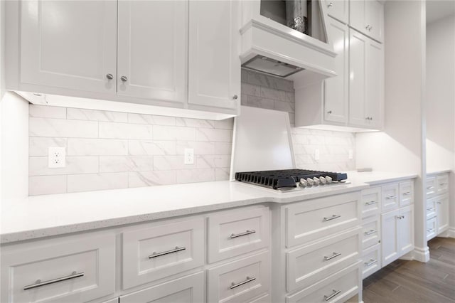 kitchen featuring premium range hood, tasteful backsplash, white cabinets, dark hardwood / wood-style flooring, and light stone countertops