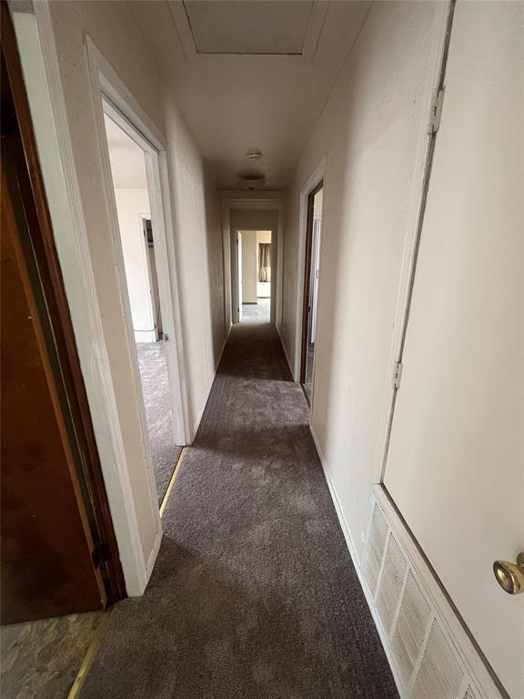 hallway featuring dark colored carpet