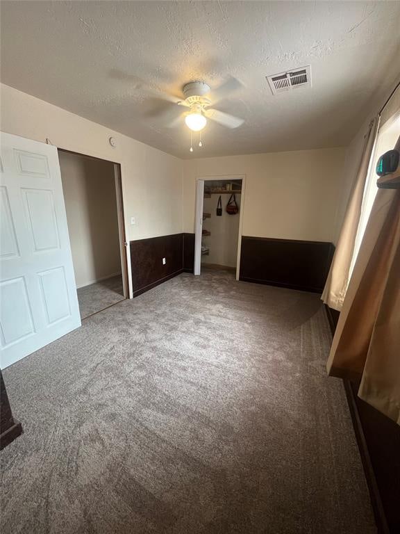 unfurnished bedroom with carpet flooring, a textured ceiling, a closet, and ceiling fan