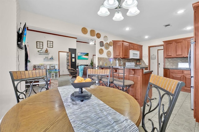 tiled dining area with ceiling fan with notable chandelier and sink