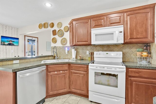 kitchen with decorative backsplash, white appliances, sink, and light tile patterned floors