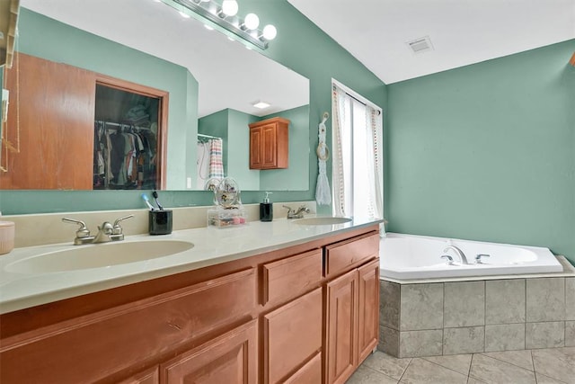 bathroom featuring tile patterned flooring, vanity, and tiled tub