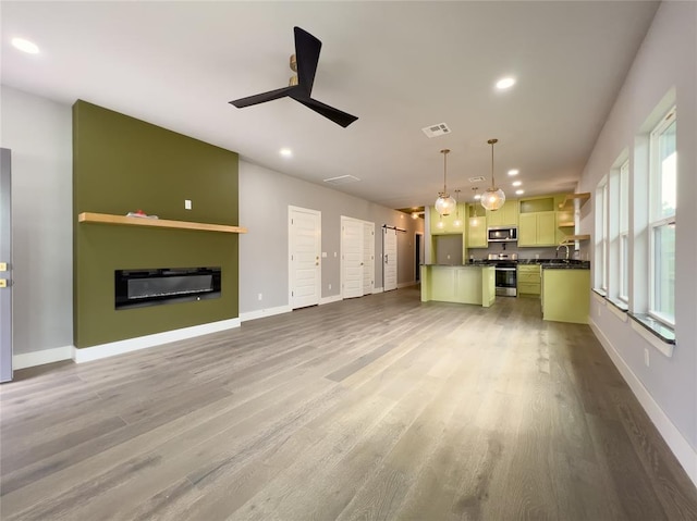 unfurnished living room featuring hardwood / wood-style flooring, ceiling fan, and sink