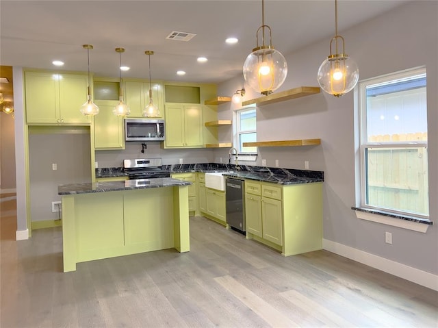 kitchen with appliances with stainless steel finishes, light wood-type flooring, pendant lighting, and sink