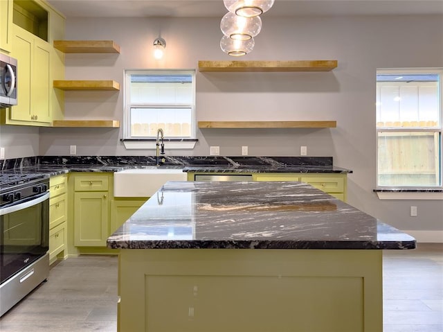 kitchen featuring appliances with stainless steel finishes, a center island, dark stone counters, and a healthy amount of sunlight