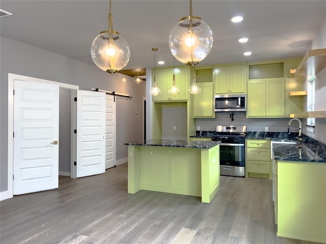 kitchen with a center island, sink, hanging light fixtures, a barn door, and appliances with stainless steel finishes