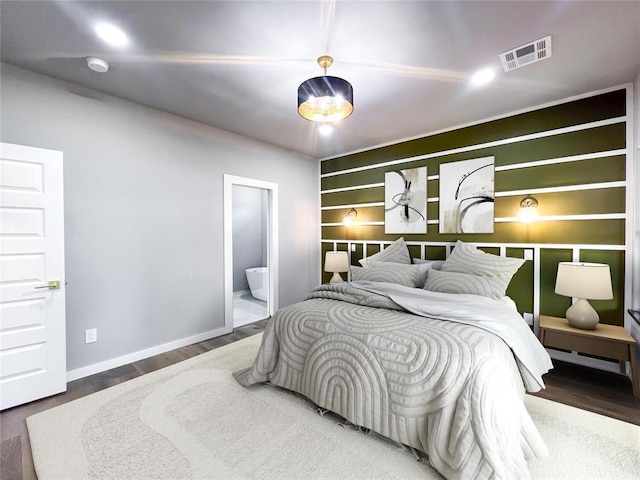 bedroom featuring ensuite bath and wood-type flooring