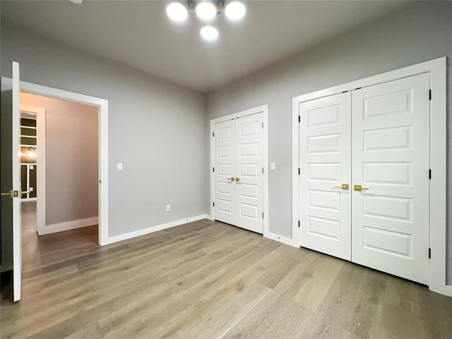 unfurnished bedroom featuring multiple closets and light hardwood / wood-style floors