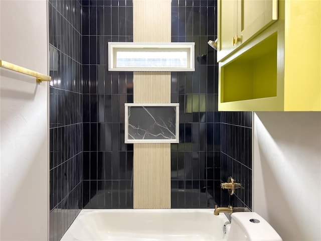 bathroom featuring tiled shower / bath combo and toilet