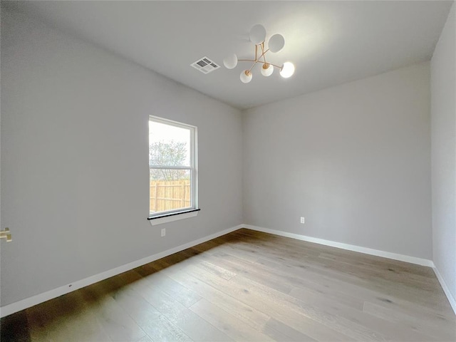 unfurnished room featuring a notable chandelier and light hardwood / wood-style flooring