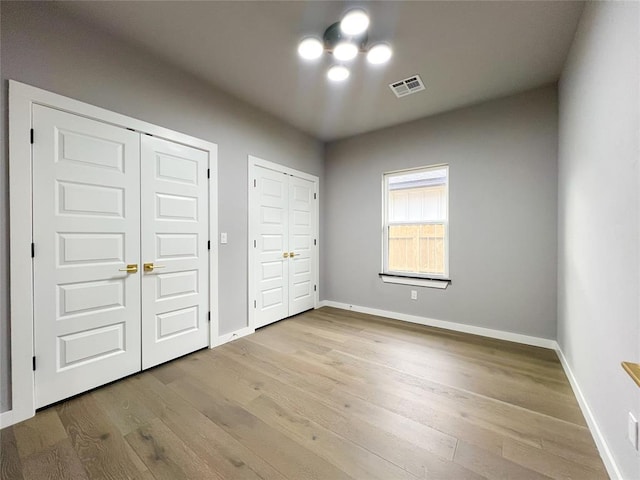 unfurnished bedroom featuring light hardwood / wood-style floors and multiple closets