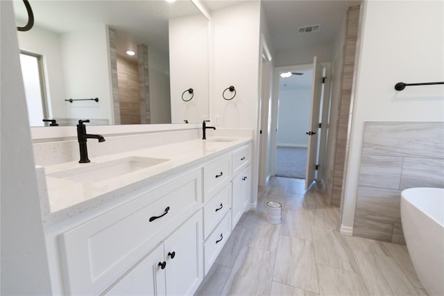 bathroom featuring ceiling fan, a washtub, tile walls, and vanity