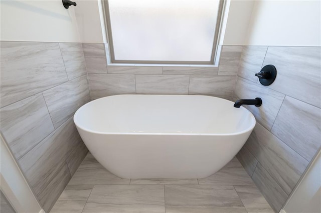 bathroom with a bathing tub and tile walls