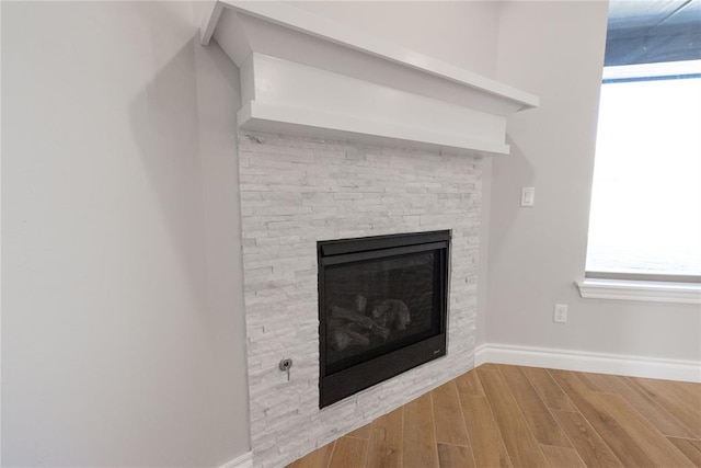 room details featuring a fireplace, wood finished floors, and baseboards