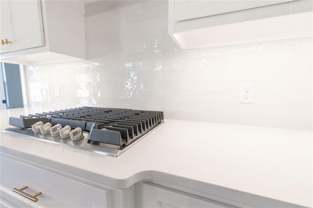 room details featuring tasteful backsplash, white cabinets, light countertops, and stainless steel gas stovetop