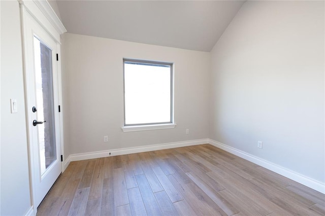 empty room featuring baseboards, lofted ceiling, and light wood-style floors