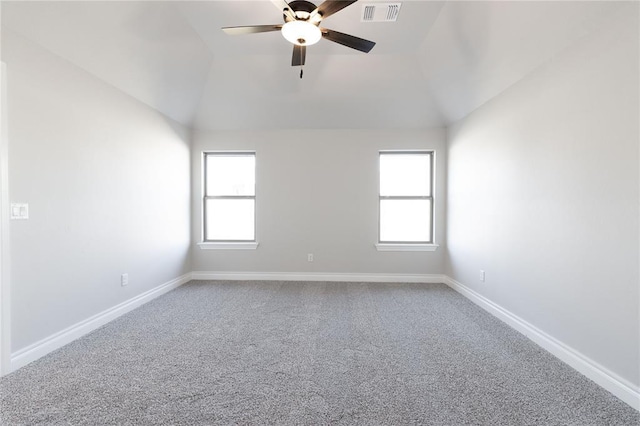 carpeted empty room featuring a healthy amount of sunlight, baseboards, visible vents, and lofted ceiling