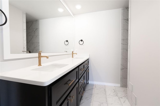 bathroom with marble finish floor, a sink, baseboards, and double vanity