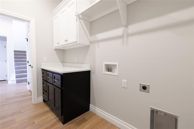 washroom featuring washer hookup, cabinet space, light wood-style flooring, hookup for an electric dryer, and baseboards