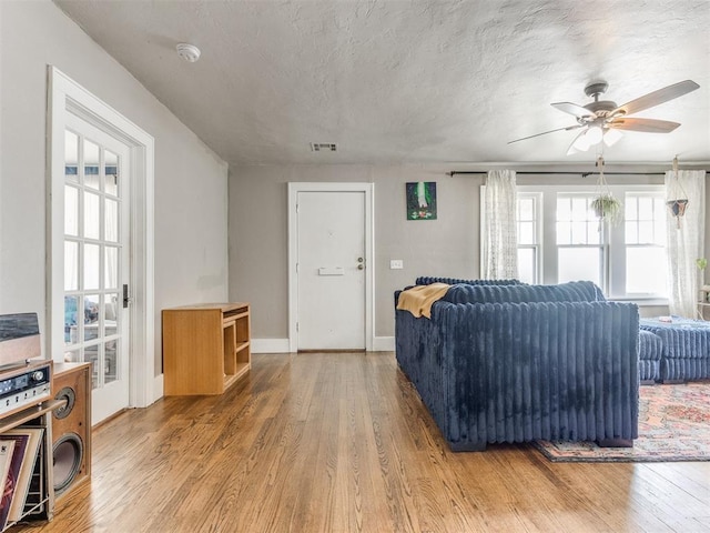 living room featuring ceiling fan, wood-type flooring, and a textured ceiling