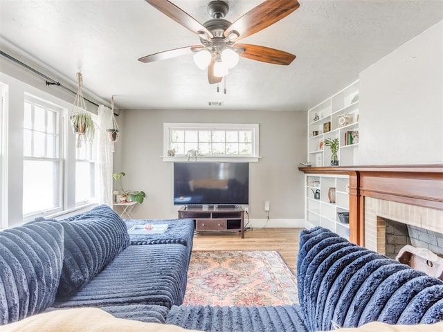 living room featuring ceiling fan, wood-type flooring, and a fireplace