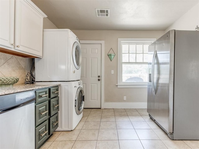 laundry room featuring stacked washer / drying machine and light tile patterned flooring