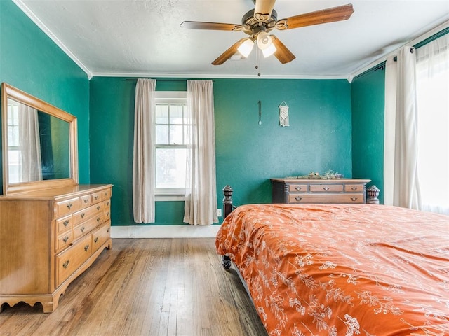 bedroom with ceiling fan, ornamental molding, and hardwood / wood-style flooring