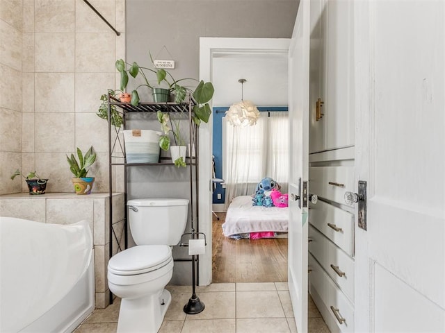 bathroom with toilet, tile patterned floors, and tile walls