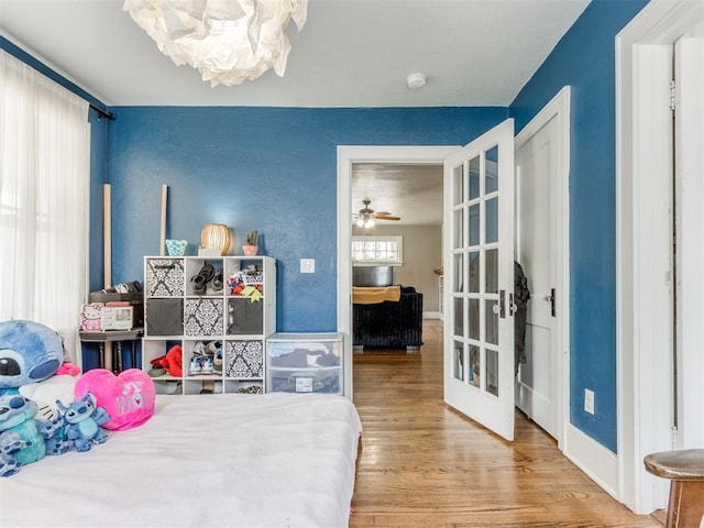 bedroom with wood-type flooring, french doors, and multiple windows