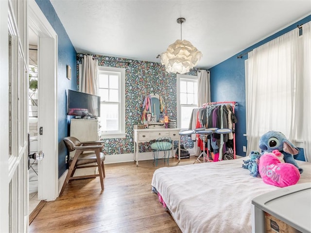 bedroom with a chandelier, wood-type flooring, and multiple windows