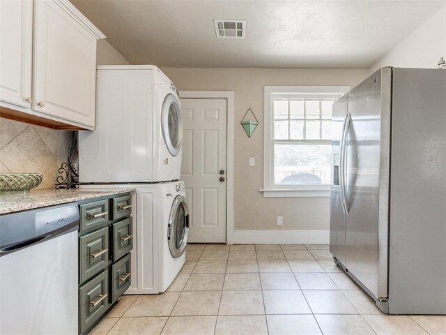 2045 NW 21st St, Oklahoma City, OK 73106 - laundry room with stacked washer and clothes dryer, light tile patterned flooring, and baseboards