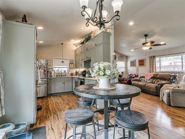 dining space featuring a wealth of natural light, ceiling fan with notable chandelier, and light wood-type flooring