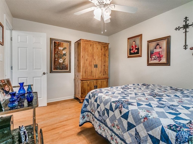 bedroom with a textured ceiling, light hardwood / wood-style flooring, and ceiling fan