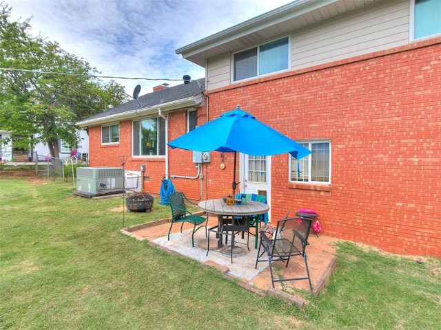 rear view of property featuring a patio, a fire pit, cooling unit, and a lawn